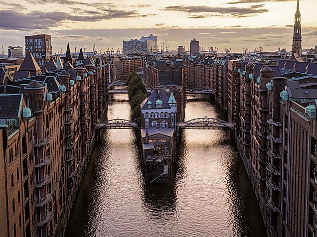 Blick auf das Wasserschloss in der Hamburger Speicherstadt bei Sonnenuntergang, mit Elbphilharmonie im Hintergrund